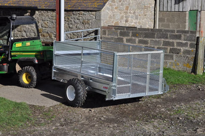 Logic ATV Trailer parked next to a green UTV on a concrete surface with a stone wall in the background.