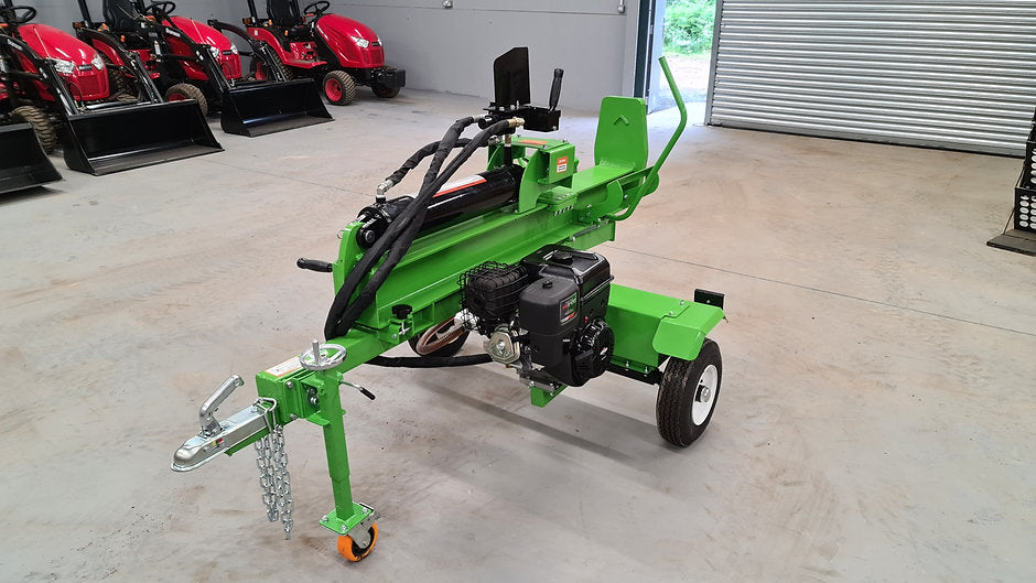 Green FarmMaster Goliath log splitter in a warehouse setting with red tractors in the background