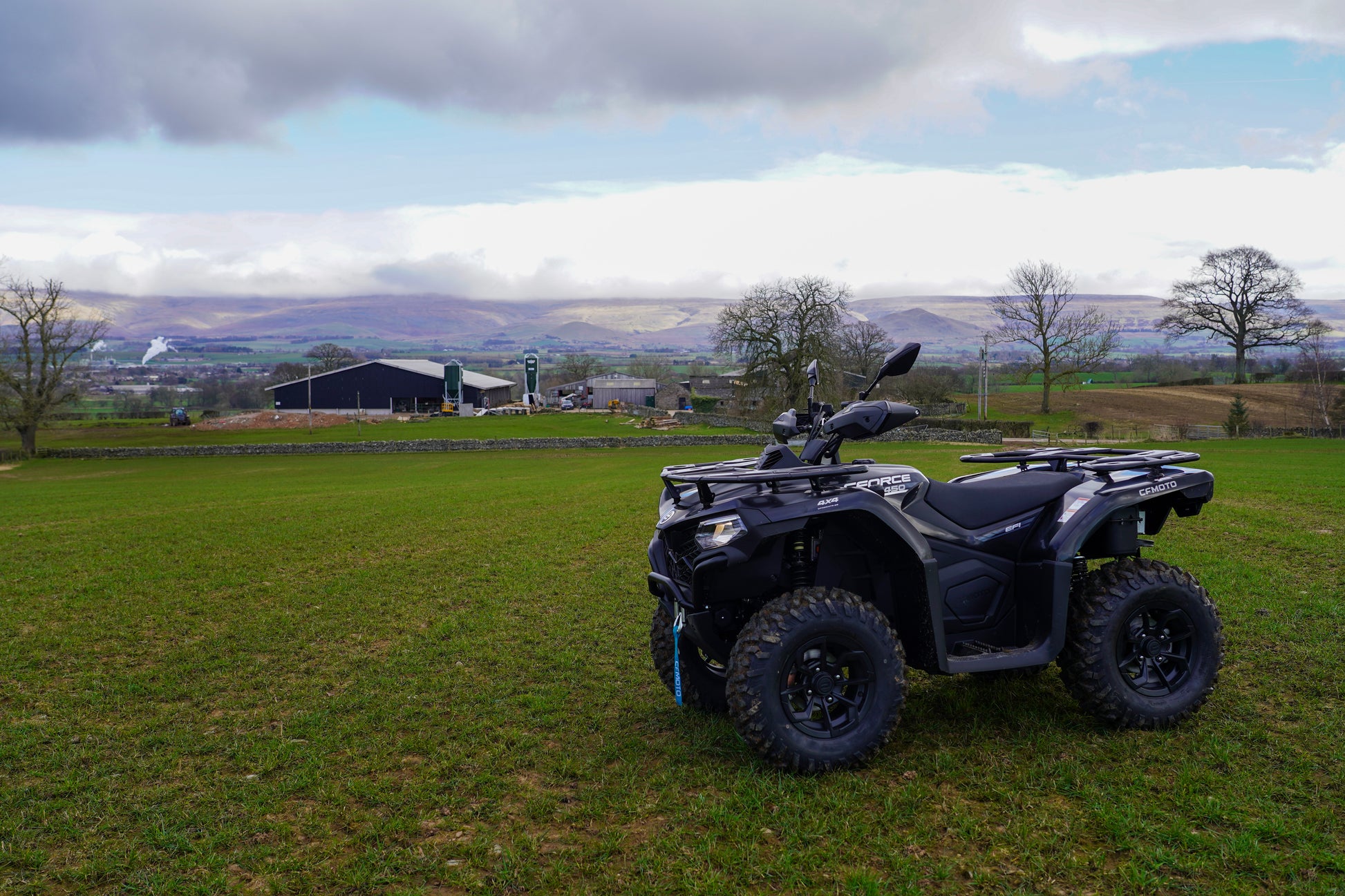 Black CFMOTO ATV parked on grass with a scenic landscape in the background