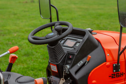 Close-up of an Avenger tractor's steering wheel and dashboard with a grassy background