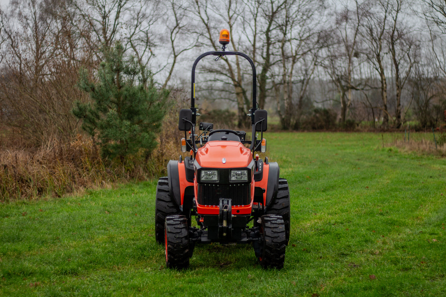 Avenger compact tractor in a grassy field with trees in the background
