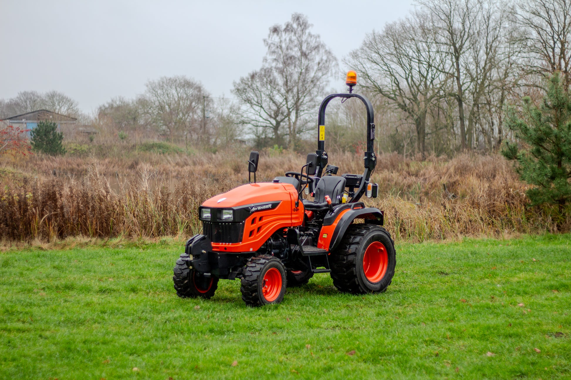 Avenger compact tractor on a grassy field with trees in the background