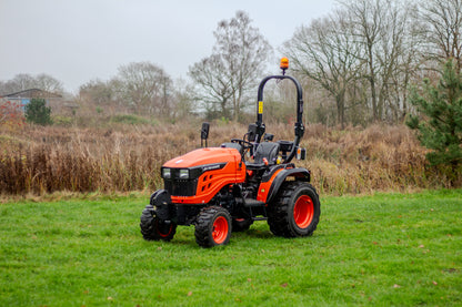 Avenger compact tractor on a grassy field with trees in the background