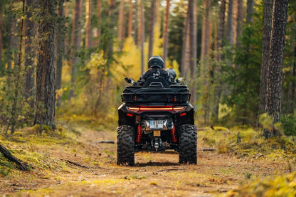 Person riding a CFMOTO quad bike through a forest path