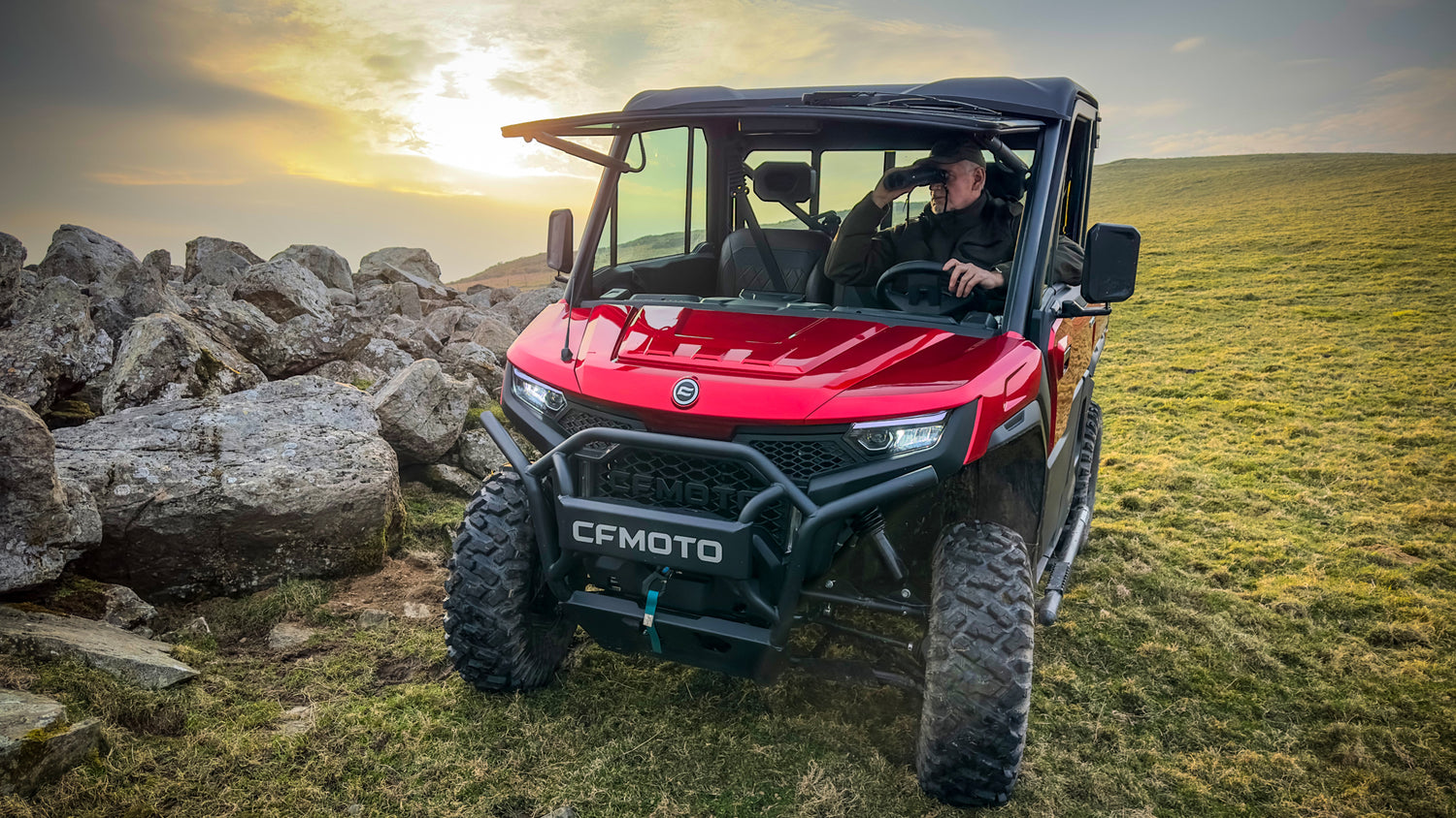 Red CFMOTO U10 Pro off-road vehicle on a grassy field with a sunset in the background