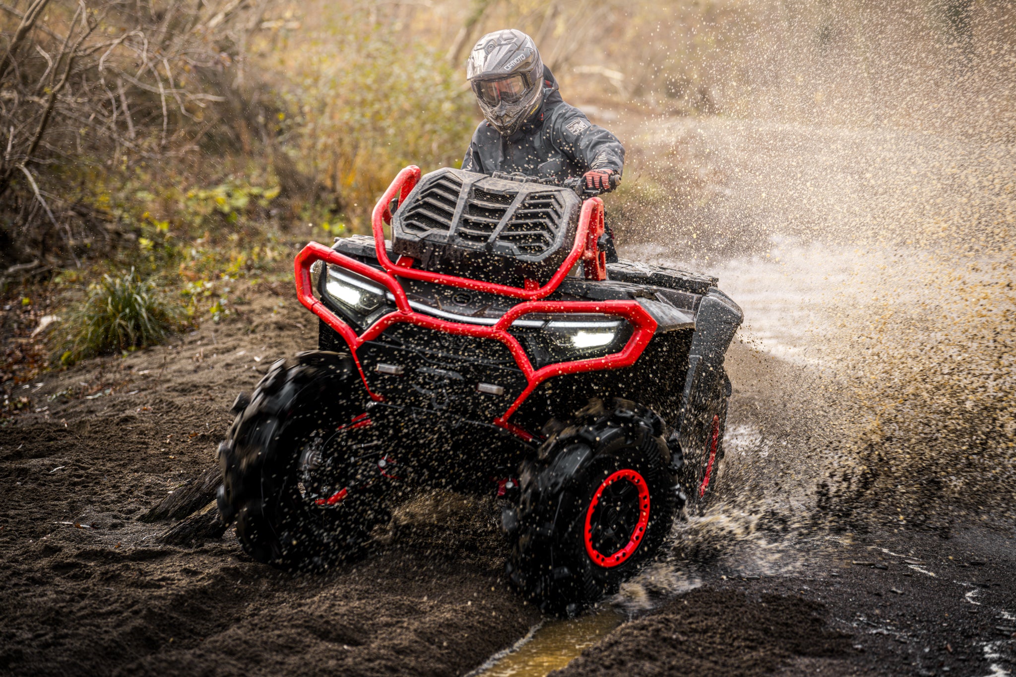 Person riding a CFMOTO 1000 MV ATV through water on a muddy trail