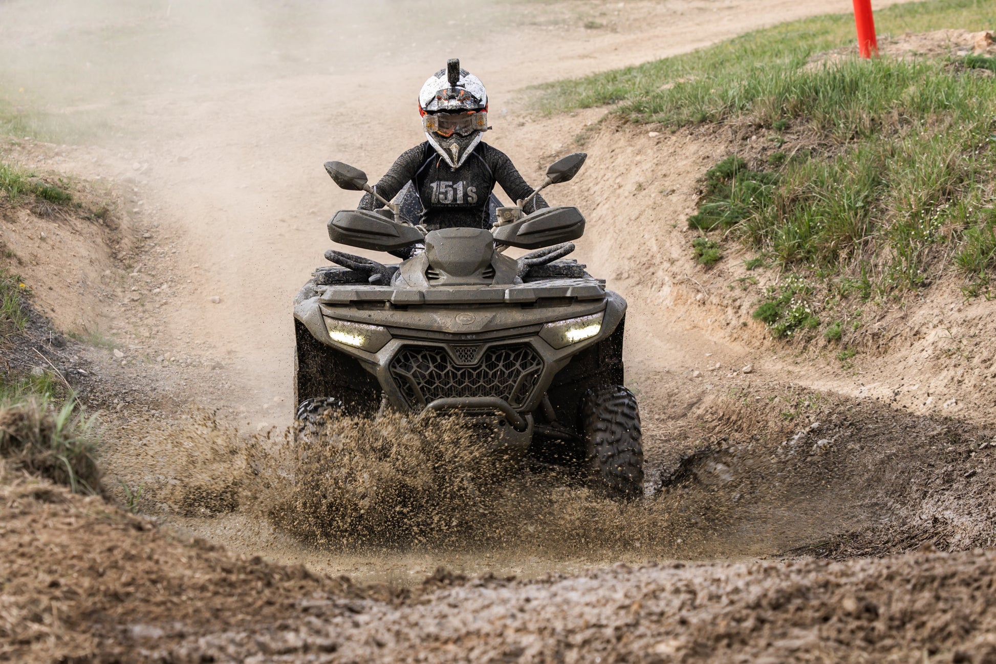 Person riding a CFMOTO ATV through a muddy trail