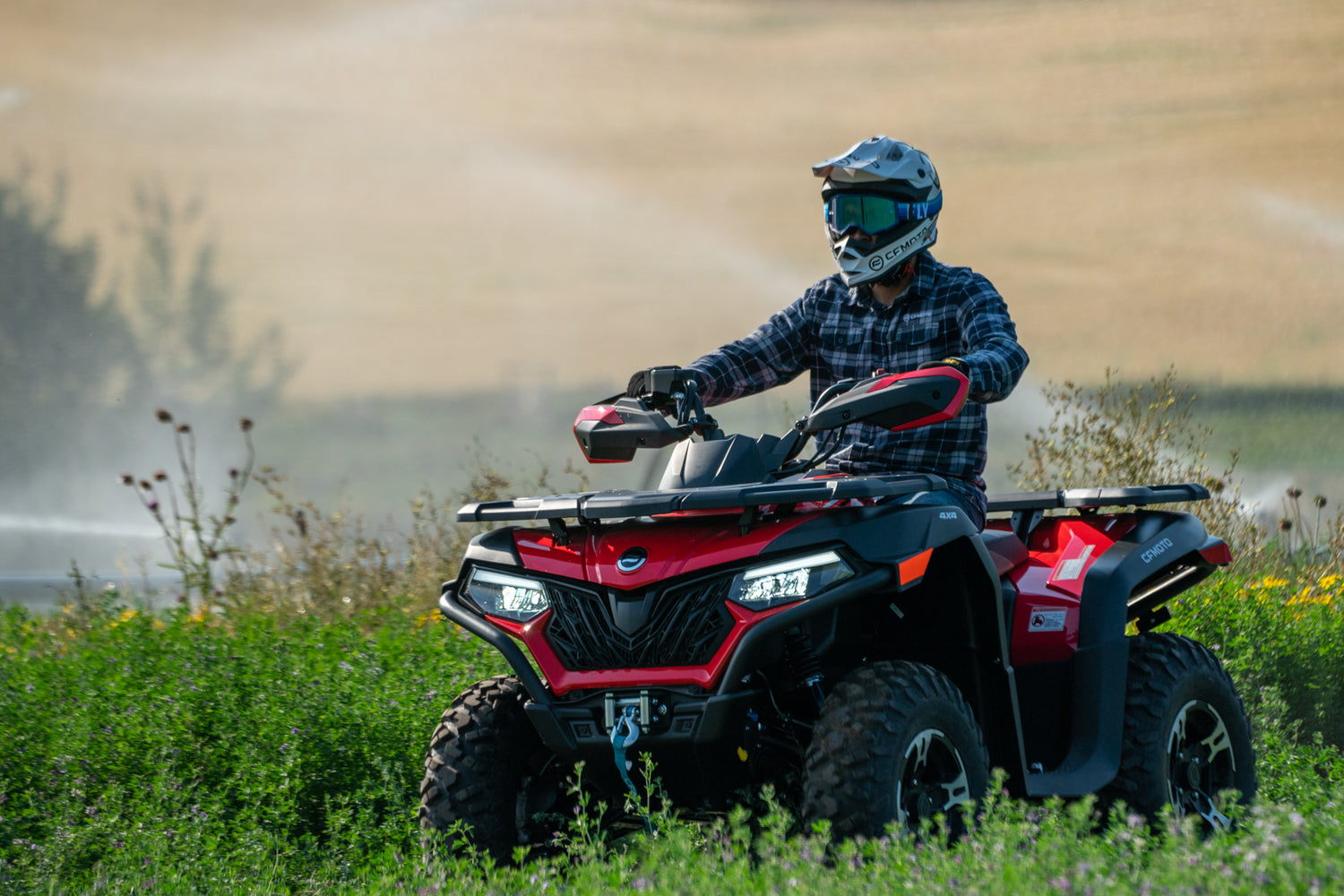 Person riding a red CFMOTO ATV in a field