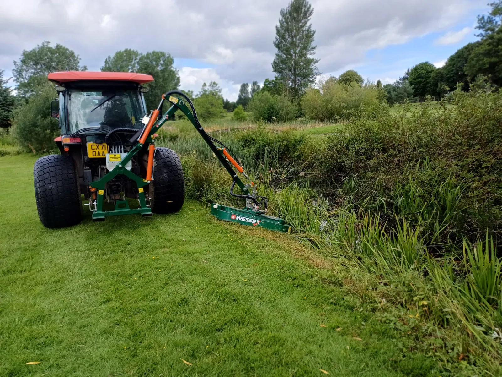 Tractor with a Wessex hedge cutter attachment in a field