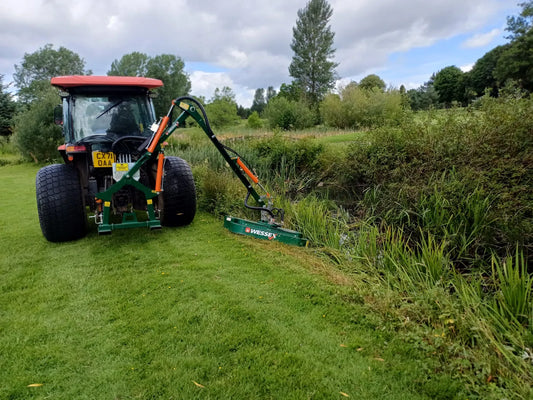Tractor with a Wessex hedge cutter attachment in a field