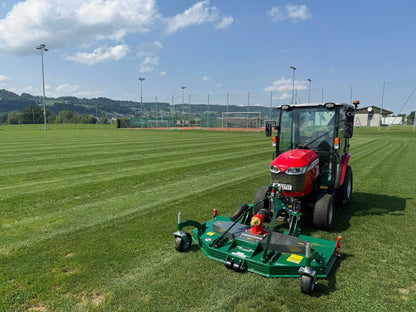 Red tractor with a wessex mower attachment on a grass field under a blue sky.