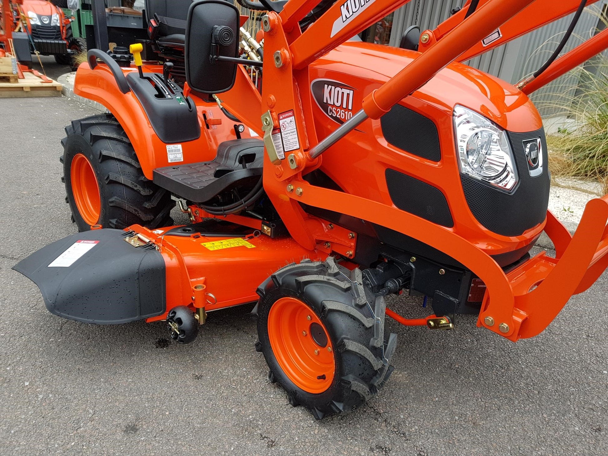 Kioti CS tractor with a front loader and mid-deck mower on a paved surface
