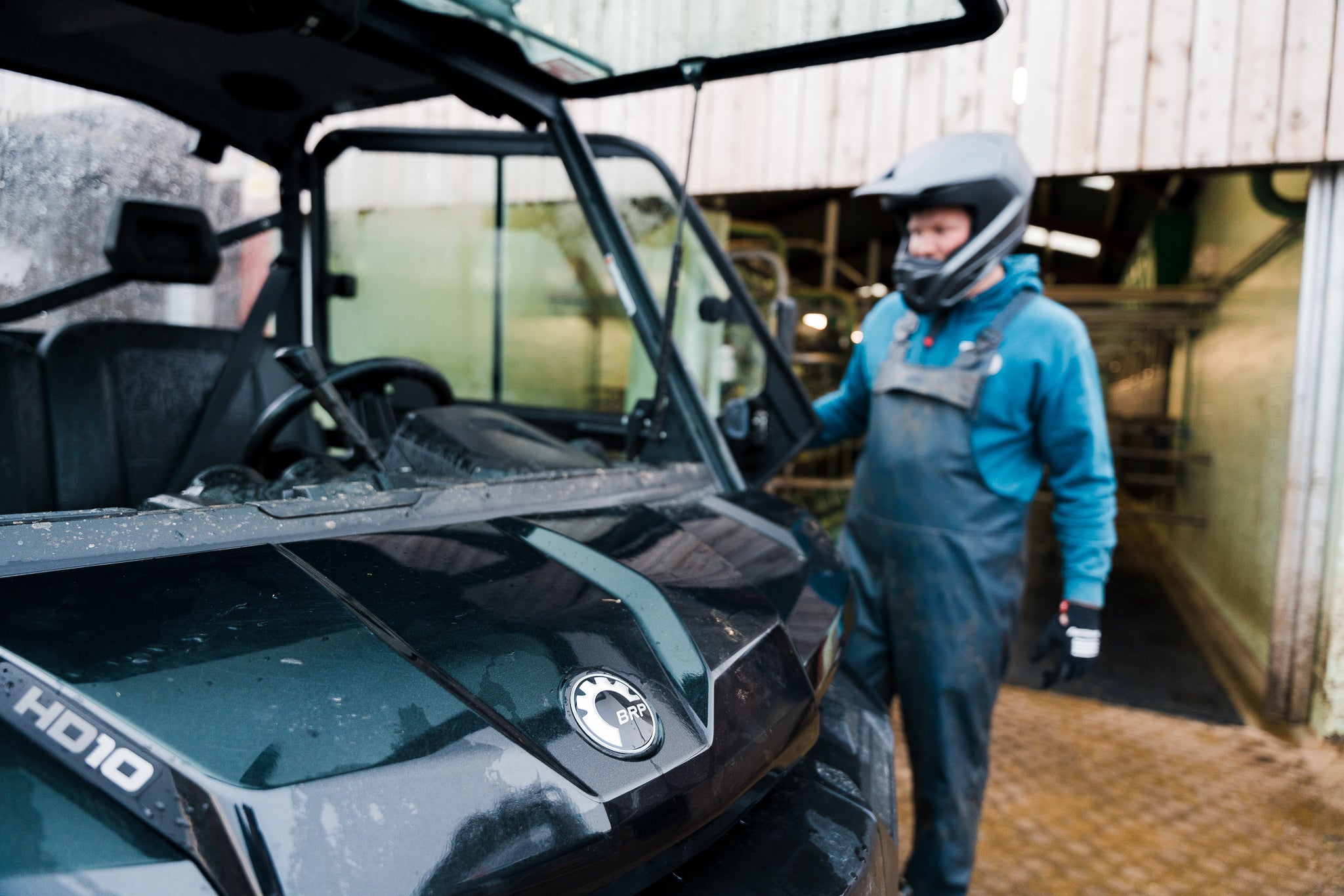 Person in protective gear standing next to a black Can-Am Traxter UTV
