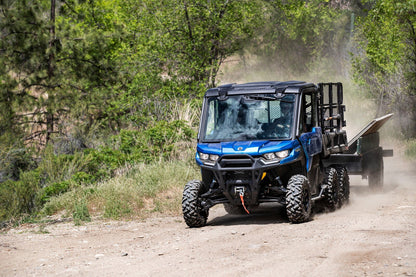Blue Can-Am UTV 6x6 utility vehicle driving on a dirt road in a forested area