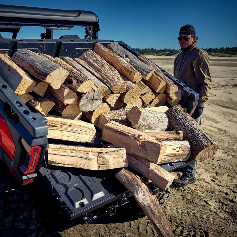 Man loading firewood into a CFMOTO UTV bed on a sunny day