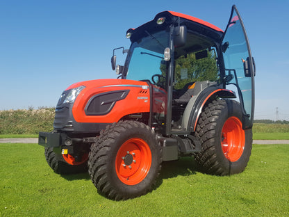 Kioti tractor on a grassy field with a clear blue sky.