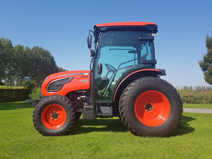 Kioti tractor on a grassy field with trees in the background