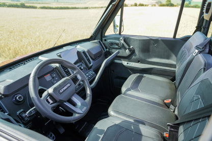 Interior of a U10 pro UTV with steering wheel and dashboard, showing a field outside the window.