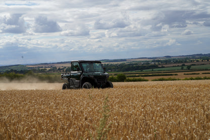 CFMOTO U10 Pro utility vehicle driving through a wheat field with a cloudy sky.
