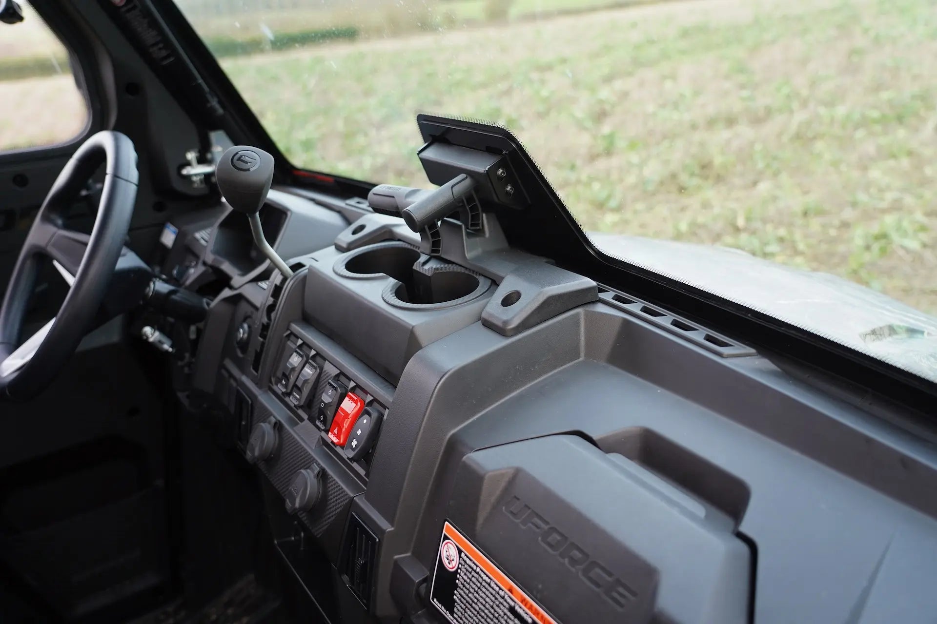 Close-up of a CFMOTO UFORCE 600 Highland UTV interior dashboard with controls and cup holders.