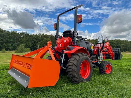 FarmMaster tractor box grader on a grassy field under a blue sky with clouds.