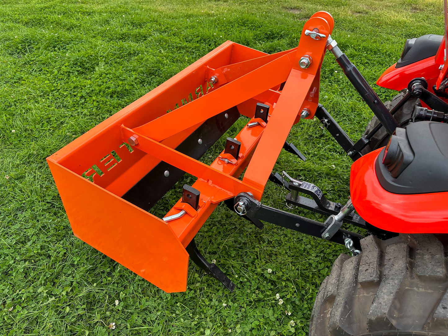 FarmMaster tractor box grader attachment on a tractor in a grassy field