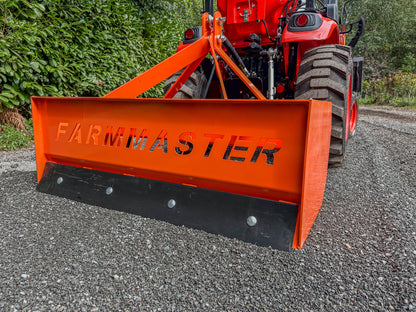 FarmMaster tractor box grader attachment on a gravel road with greenery in the background