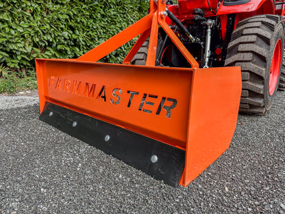 FarmMaster tractor box grader on a gravel surface with greenery in the background
