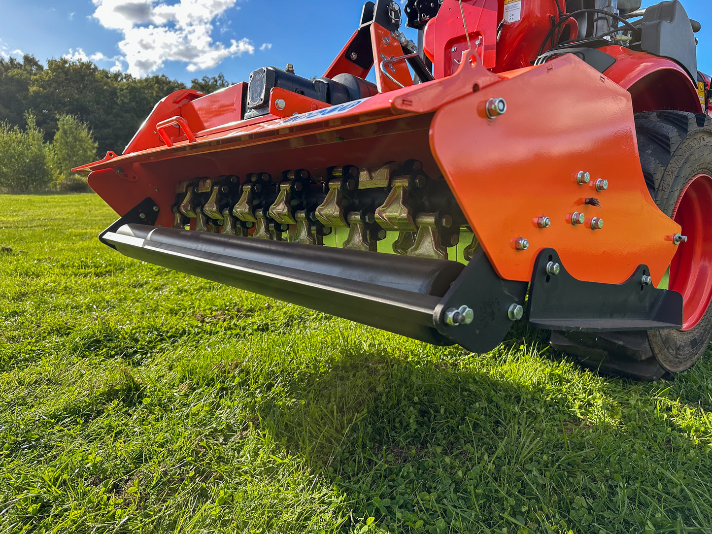 FarmMaster Flail Mower on a grassy field with trees and blue sky in the background