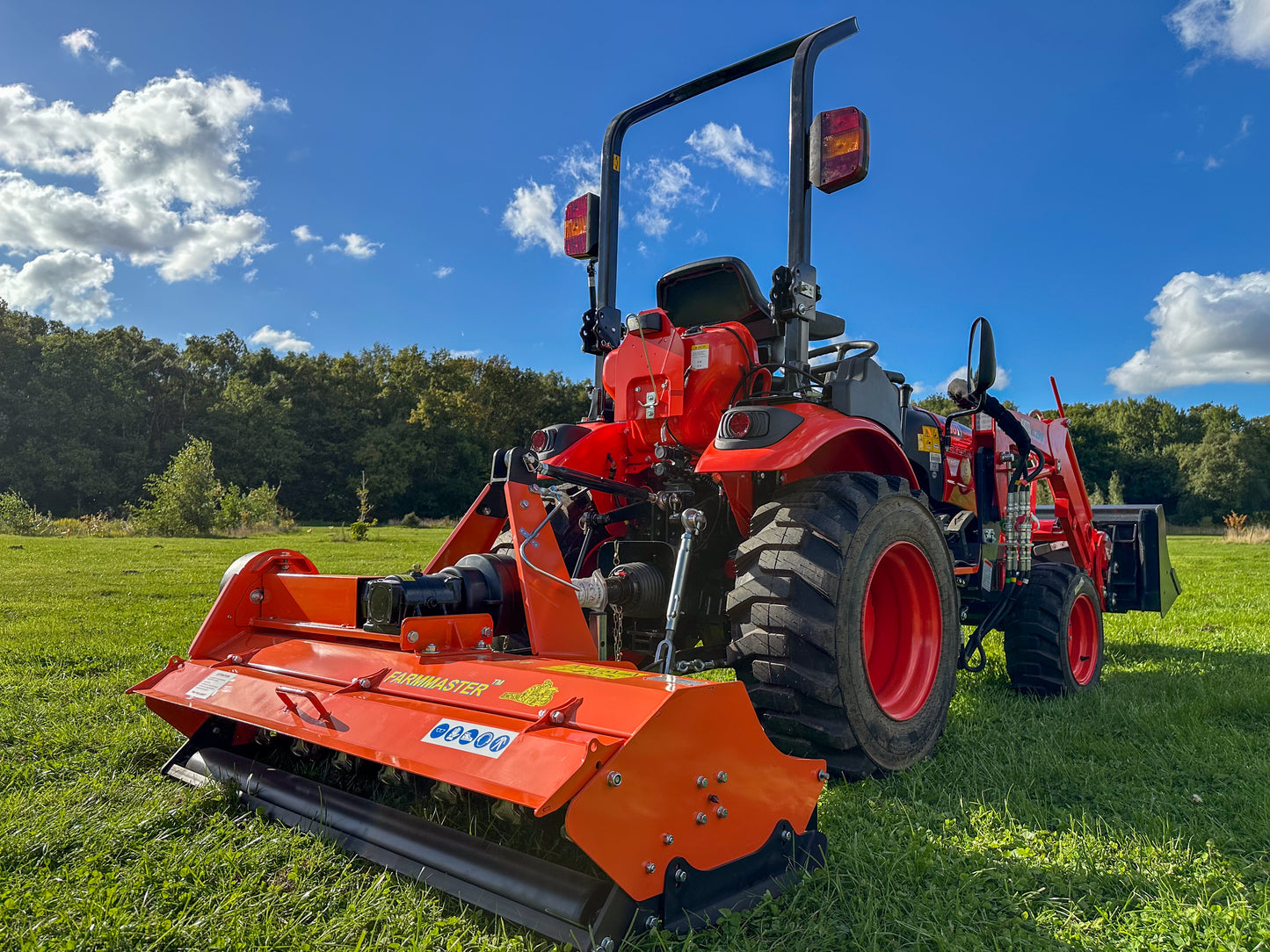 FarmMaster flail mower on a grassy field under a blue sky with clouds.