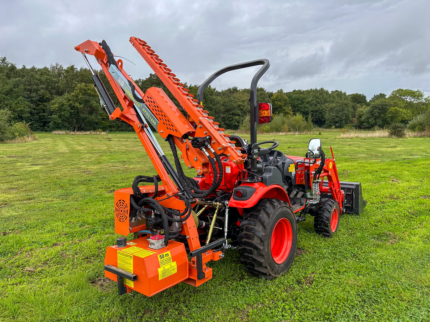 Kioti tractor with FarmMaster hedge cutter in a grassy field