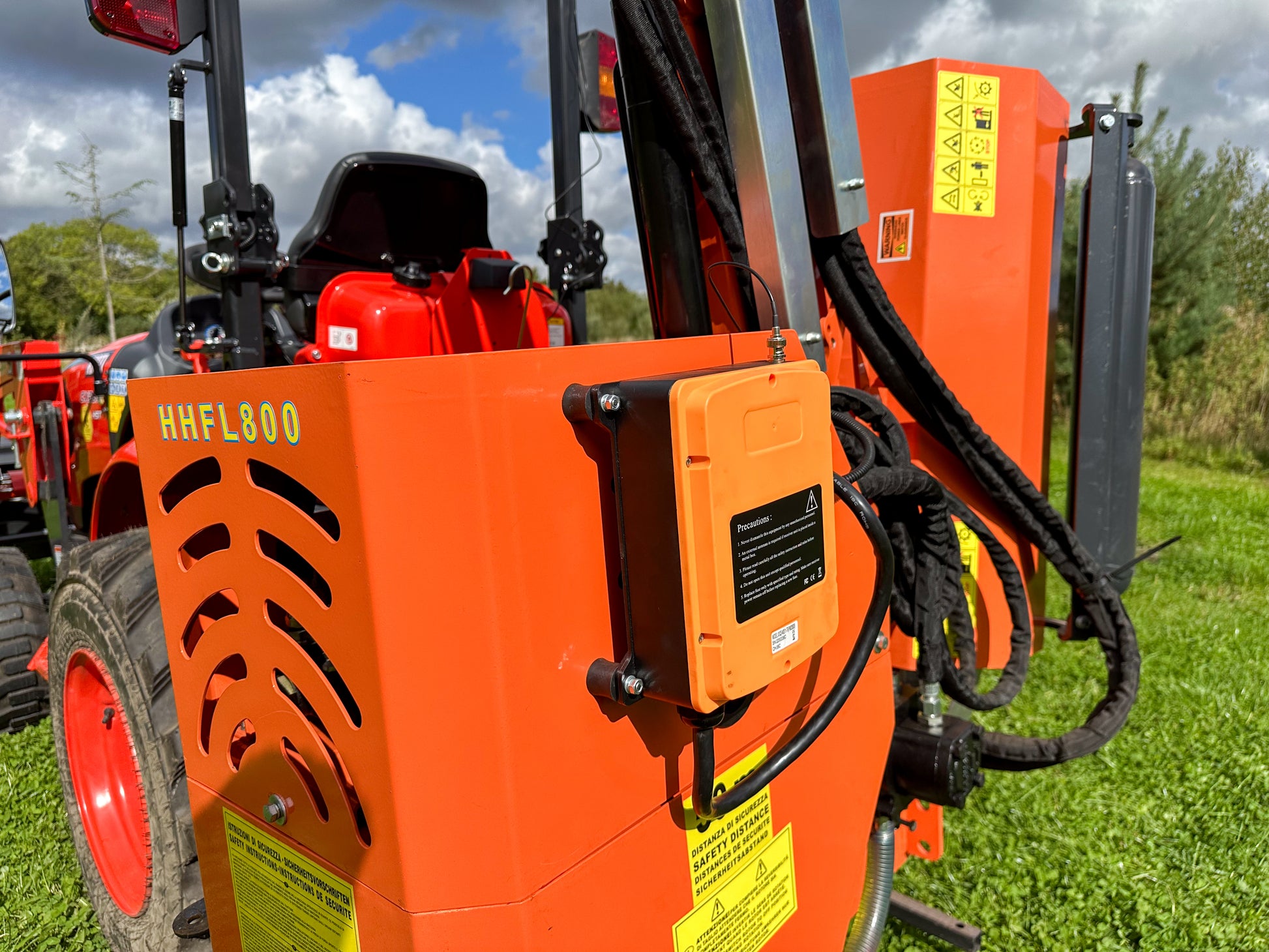Close-up of a FarmMaster tractor hedge cutter on a grassy field.