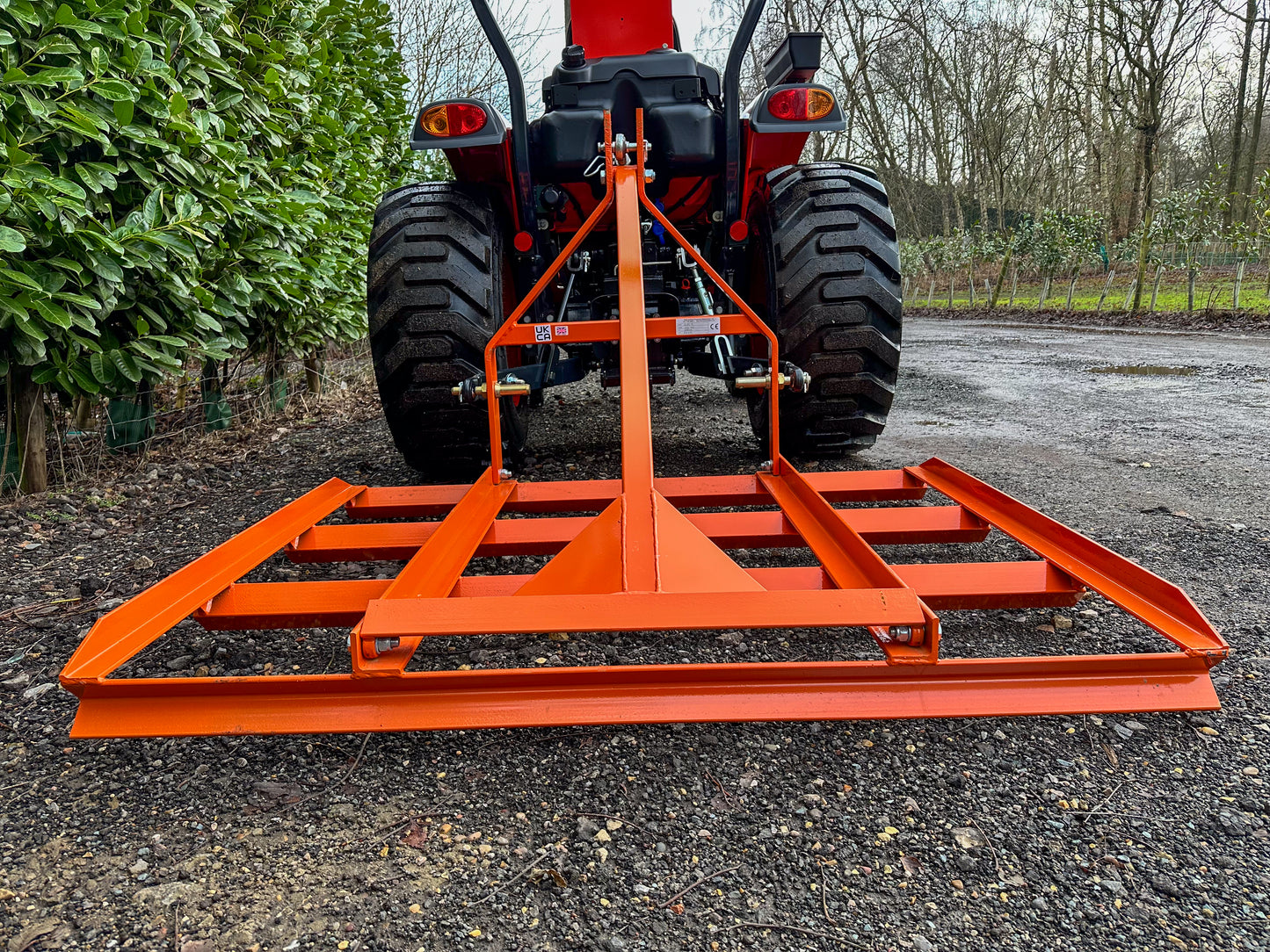 FarmMaster tractor leveller on a gravel surface with trees in the background.