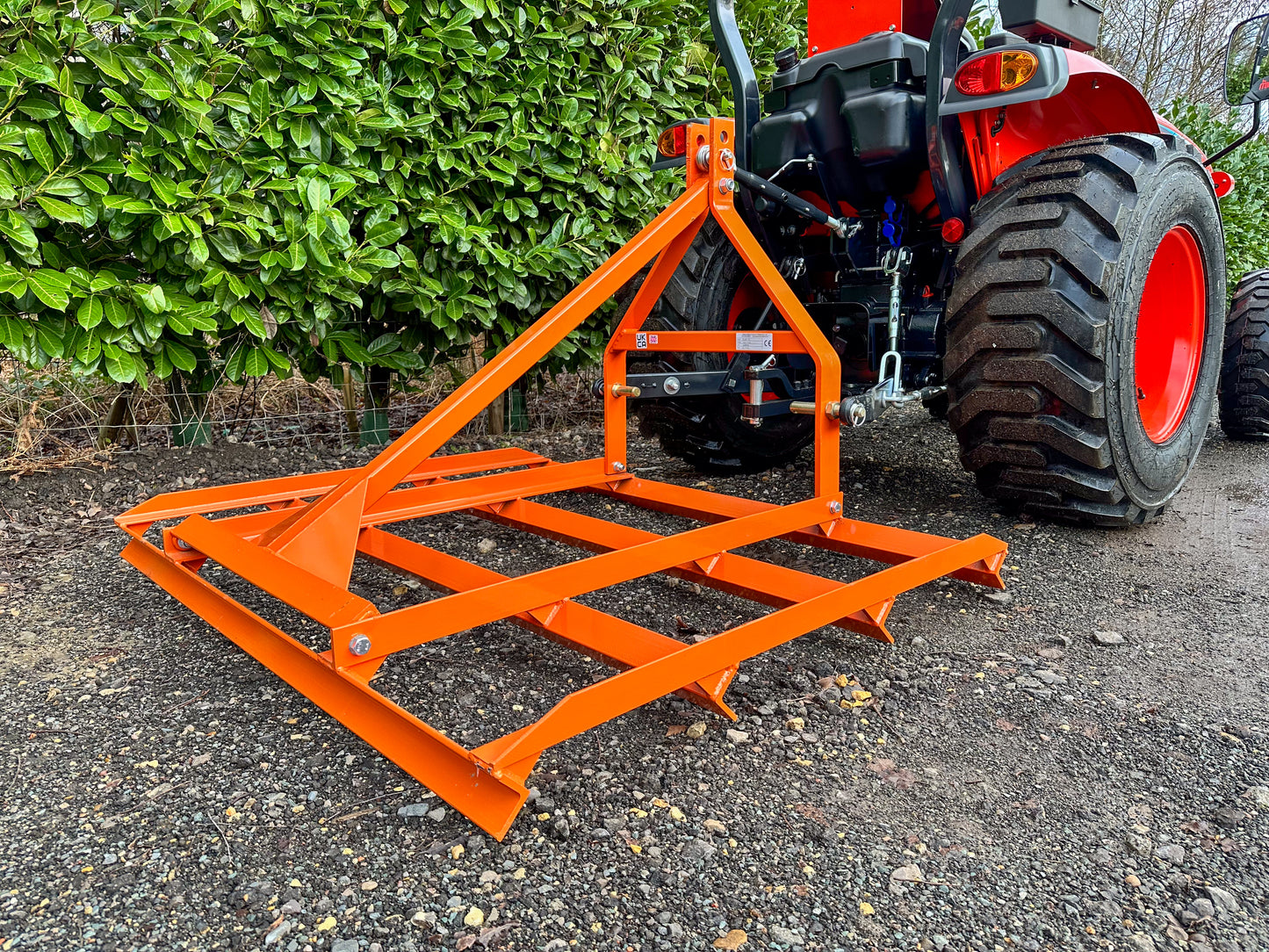 FarmMaster tractor leveller attached to a red tractor with greenery in the background