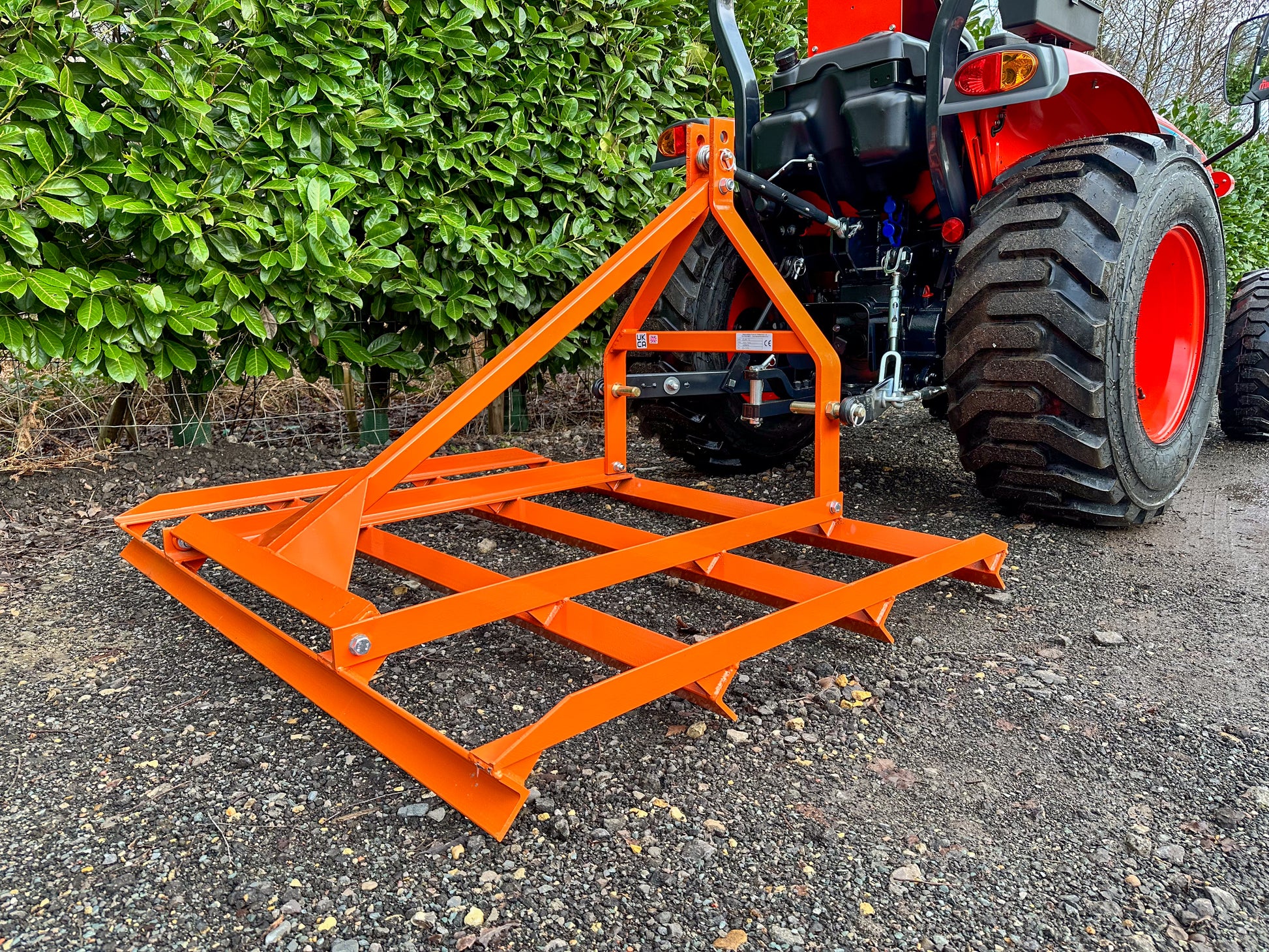 FarmMaster tractor leveller attached to a red tractor with greenery in the background