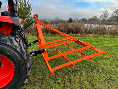 FarmMaster tractor leveller attached to a red tractor on a grassy field.
