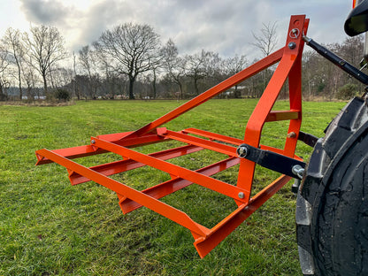 FarmMaster tractor leveller on a tractor in a field with trees and sky in the background