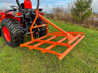 Red tractor with a FarmMaster tractor leveller on a grassy field.