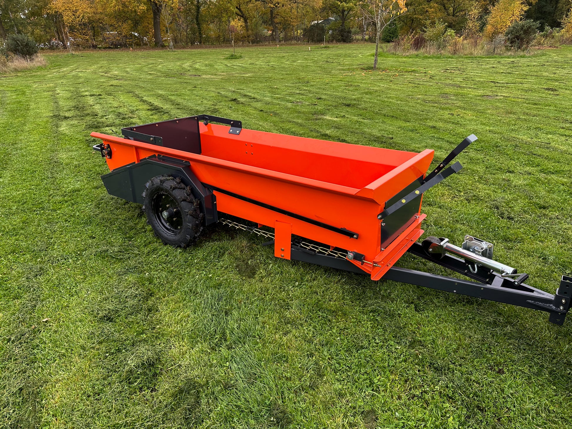 FarmMaster muck spreader on a grassy field with trees in the background