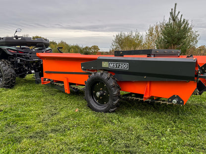 FarmMaster muck spreader on a grassy field with an ATV in the background.