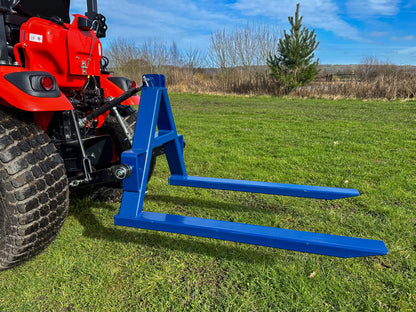 Kioti tractor with a FarmMaster tractor pallet forks attachment on a grassy field.