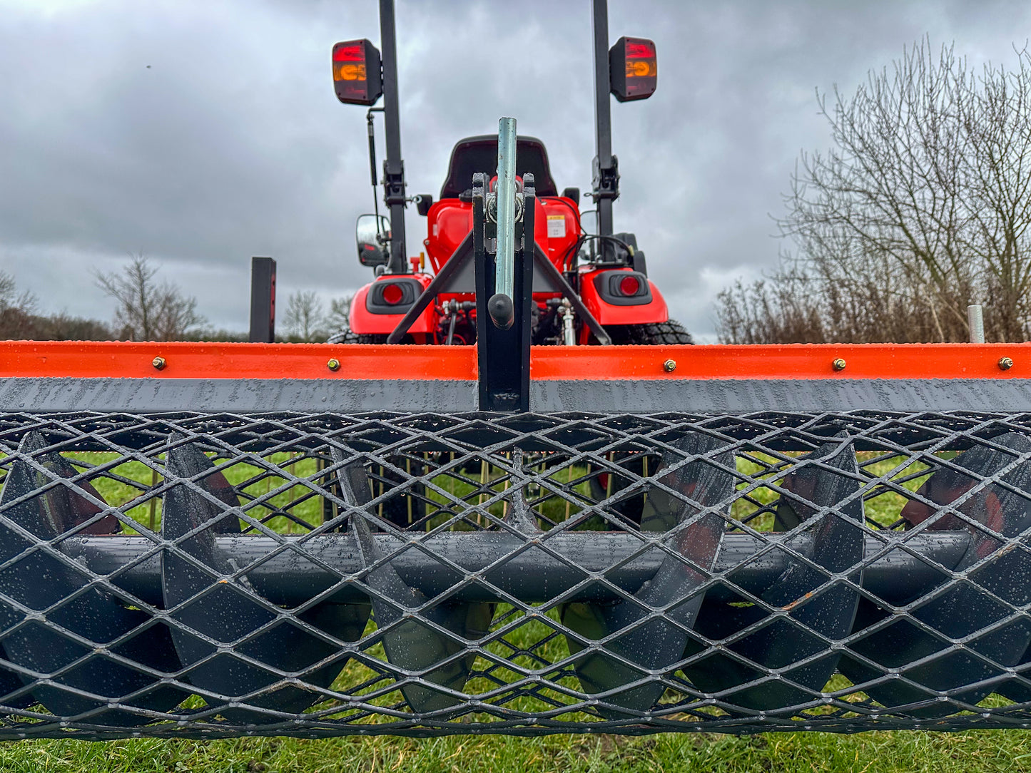 Kioti tractor with a FarmMaster tractor arena conditioner under a cloudy sky.