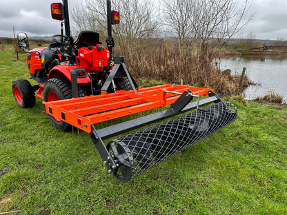 Kioti compact tractor with a FarmMaster tractor arena conditioner on a grassy field near a body of water.