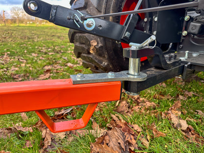 Close-up of a FarmMaster tractor land roller on a field with grass and leaves.