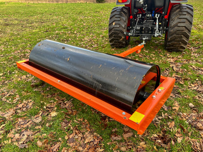 FarmMaster tractor land roller attached to a tractor on a grassy field with leaves.