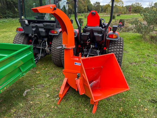 FarmMaster tractor wood chipper attached to a tractor on a grassy field
