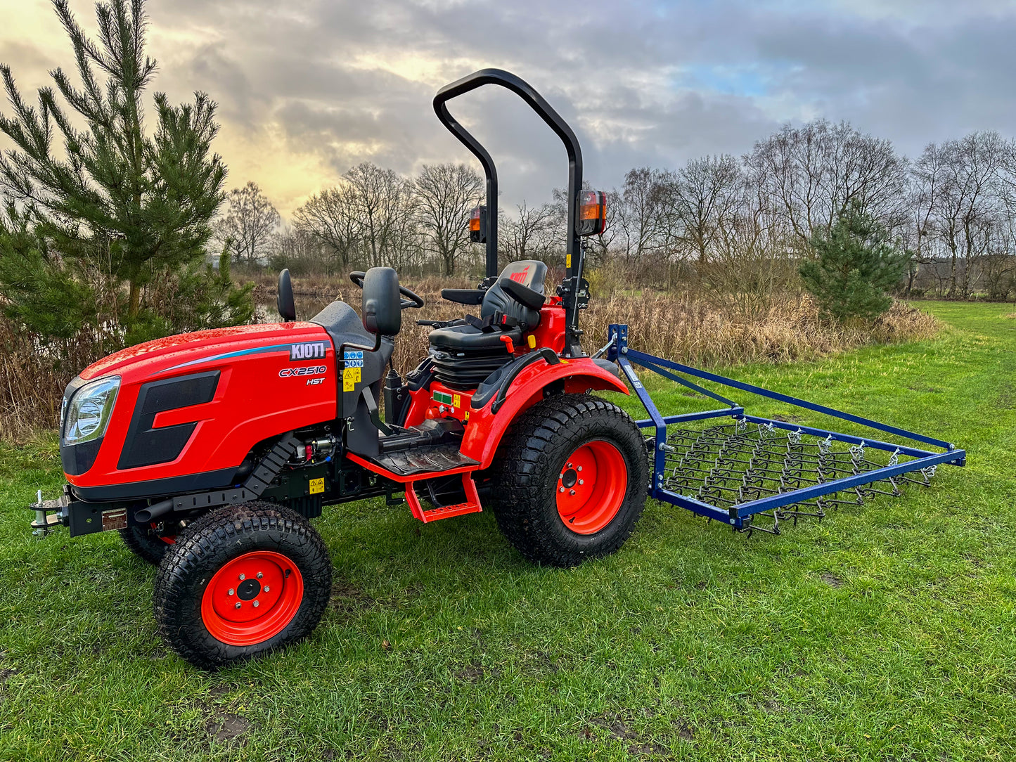 Kioti tractor with a FarmMaster Framed Chain Harrow on a grassy field