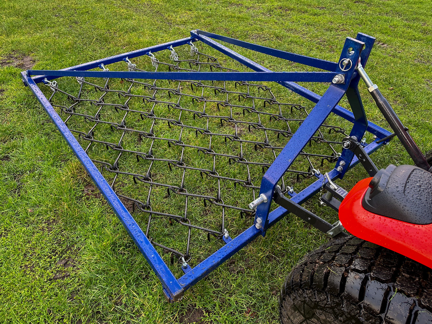 FarmMaster Framed Chain Harrow attached to a red tractor on grass