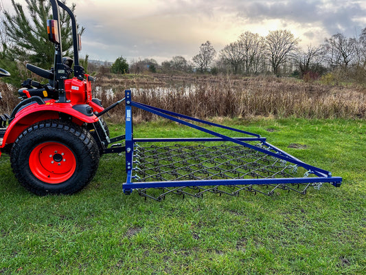 Kioti tractor with a FarmMaster Framed Chain Harrow on a grassy field.