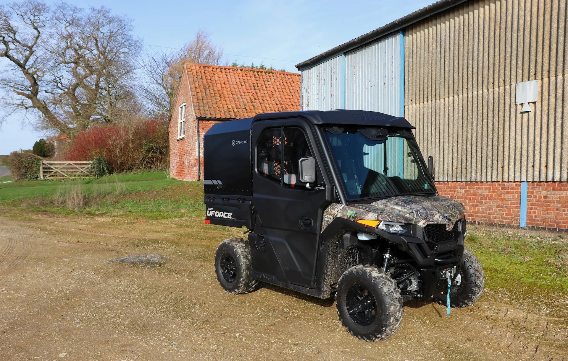 CFMOTO UFORCE 600 Highland UTV parked on a dirt road with a building and trees in the background